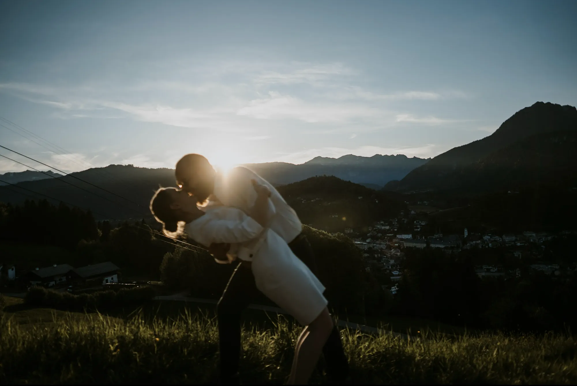 Brautpaar küsst sich im goldenen Abendlicht hoch über dem Tal von Berchtesgaden