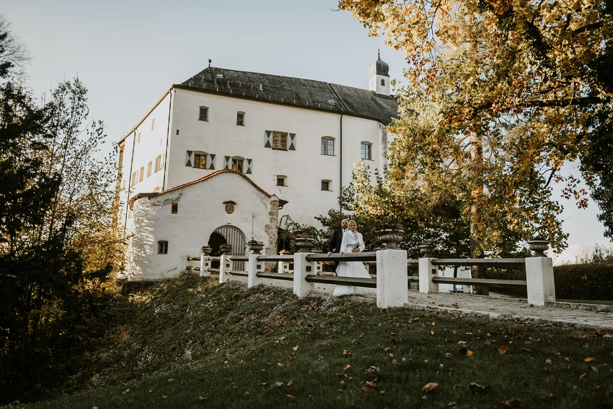 Schloss Amerang mit weißem Zaun und herbstlichen Bäumen